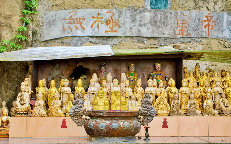 Statue dorate di divinità cinesi e calligrafia dentro l'altare di un tempio, lo stile degli interni dei santuari hainanesi di Samui