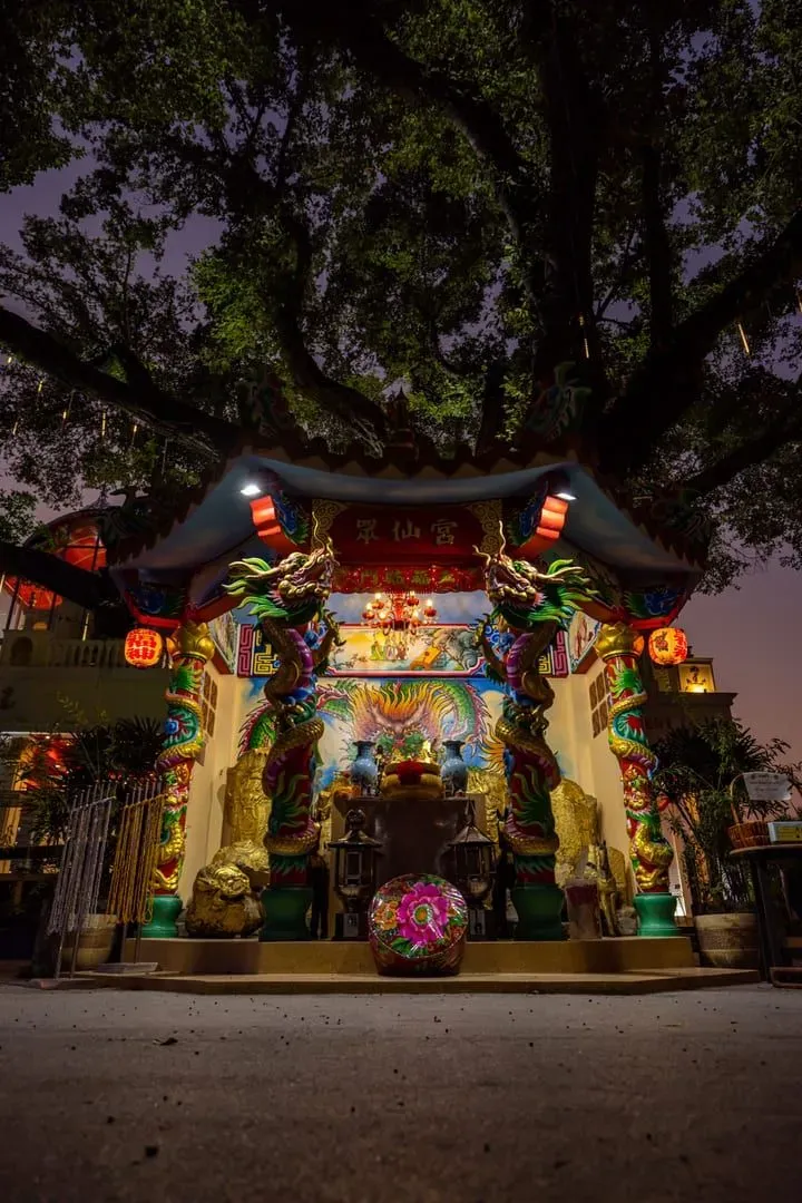 Colorful dragon sculptures on a Chinese temple entrance at dusk near a Thai coastline