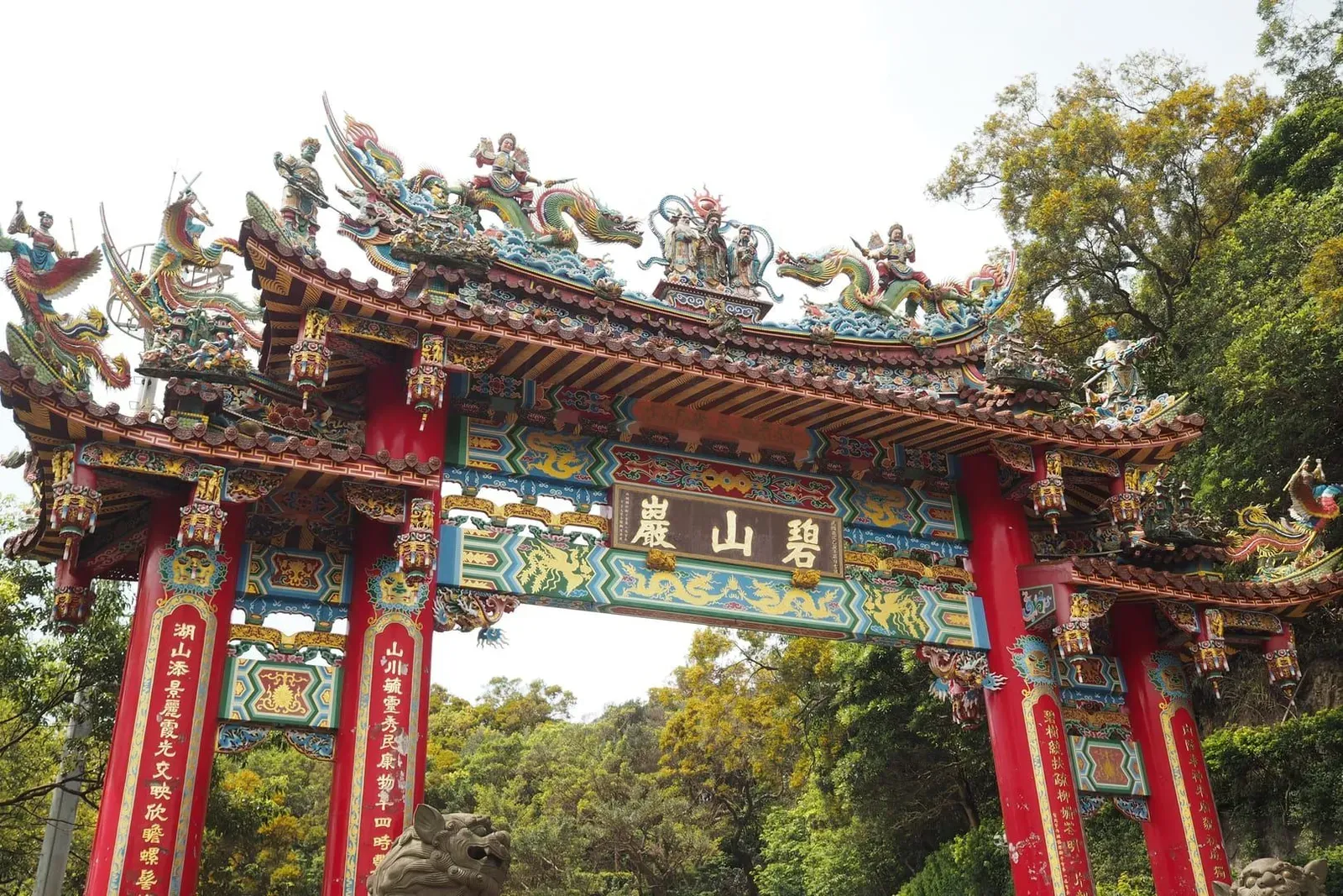 Vibrant Chinese temple gate with intricate dragon sculptures, the entrance style shared by Koh Samui's shrines