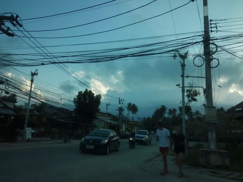 Evening street scene with cars, motorbikes and pedestrians in the village behind Choeng Mon Beach, Koh Samui