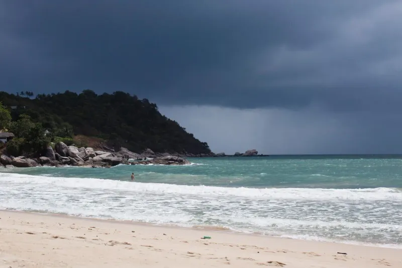 Person standing by the seashore under a dramatic dark October monsoon sky