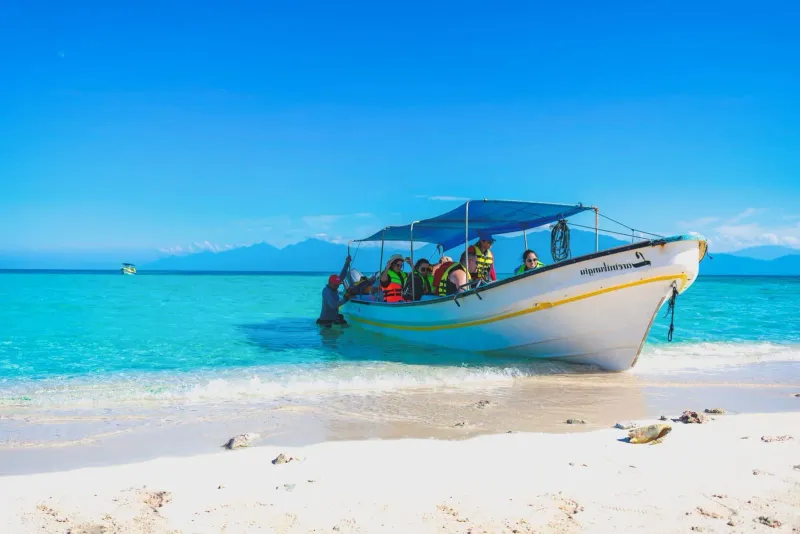 Tourists boarding a boat on a vibrant tropical beach during a Koh Samui excursion