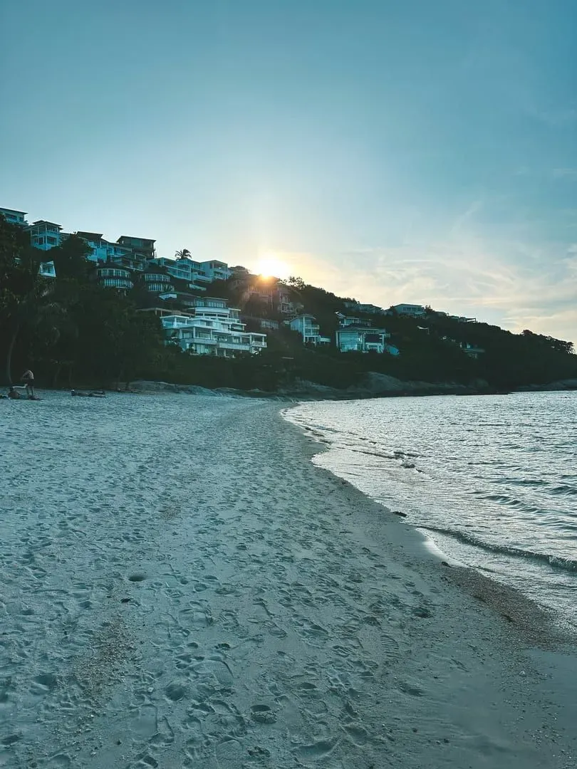 Sunrise breaking over a calm Koh Samui beach with soft orange light on flat water