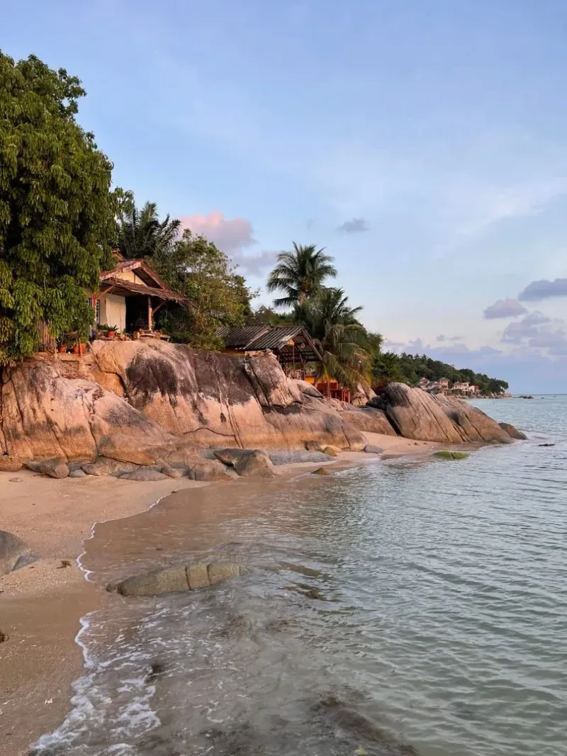 Coastal huts and palm trees at sunset on a quiet Koh Samui shoreline
