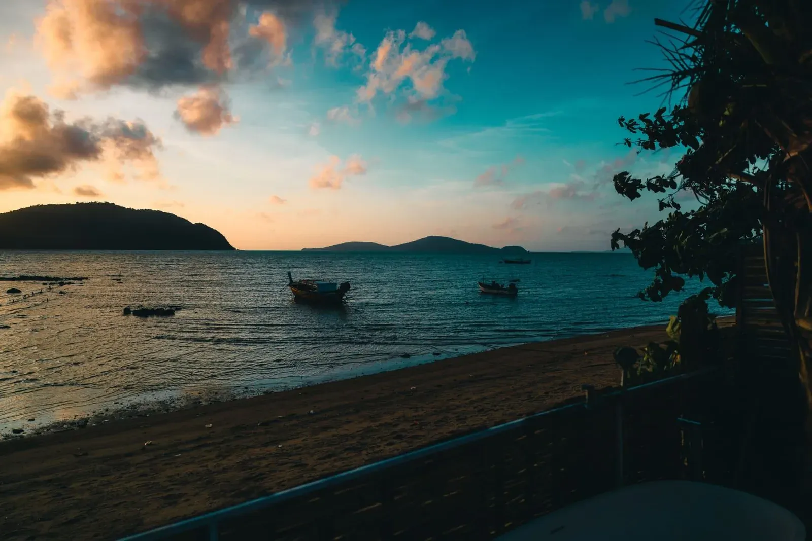 Sunset over a calm bay with boats and distant islands on Koh Samui's west coast