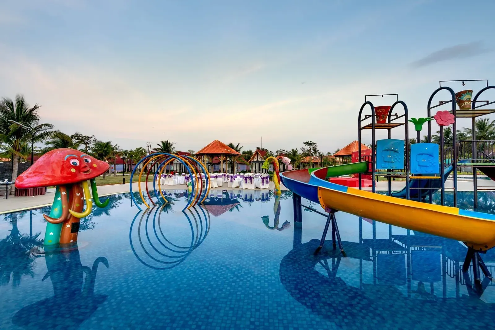 Colorful resort waterpark with slides and palm trees reflected in the pool in Koh Samui