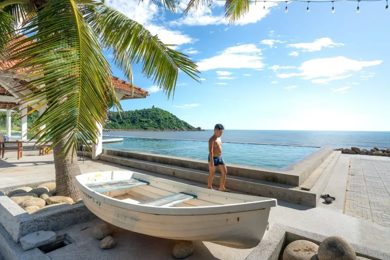 Young boy walking beside an infinity pool overlooking the ocean at a Koh Samui resort