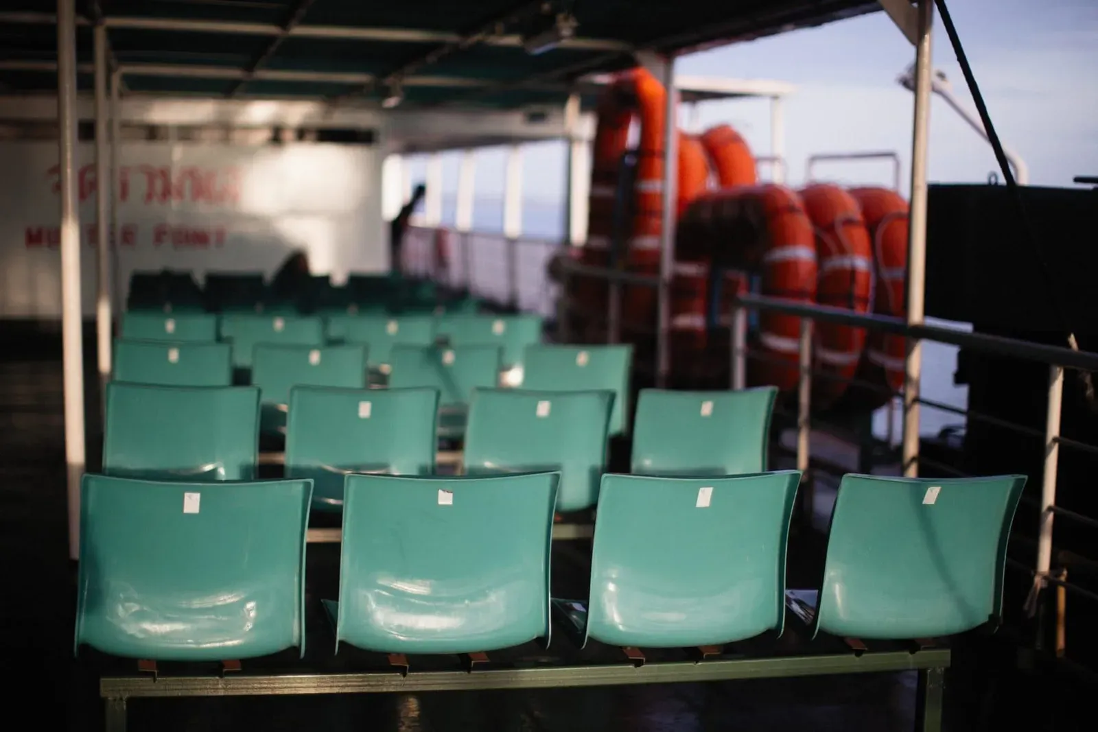 Rows of empty teal seats with lifebuoys on a passenger ferry crossing to Koh Samui