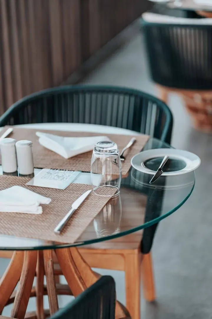 Glass-top table set with cutlery and napkins at an elegant Koh Samui restaurant