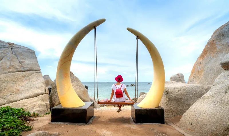 Traveler relaxing on a coastal swing overlooking calm ocean water on Koh Samui