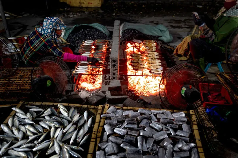 Vendors grilling fish over open flame at a bustling Koh Samui seafood market