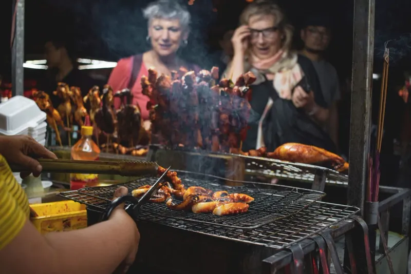 Street food barbecue scene with grilled seafood and skewers over charcoal