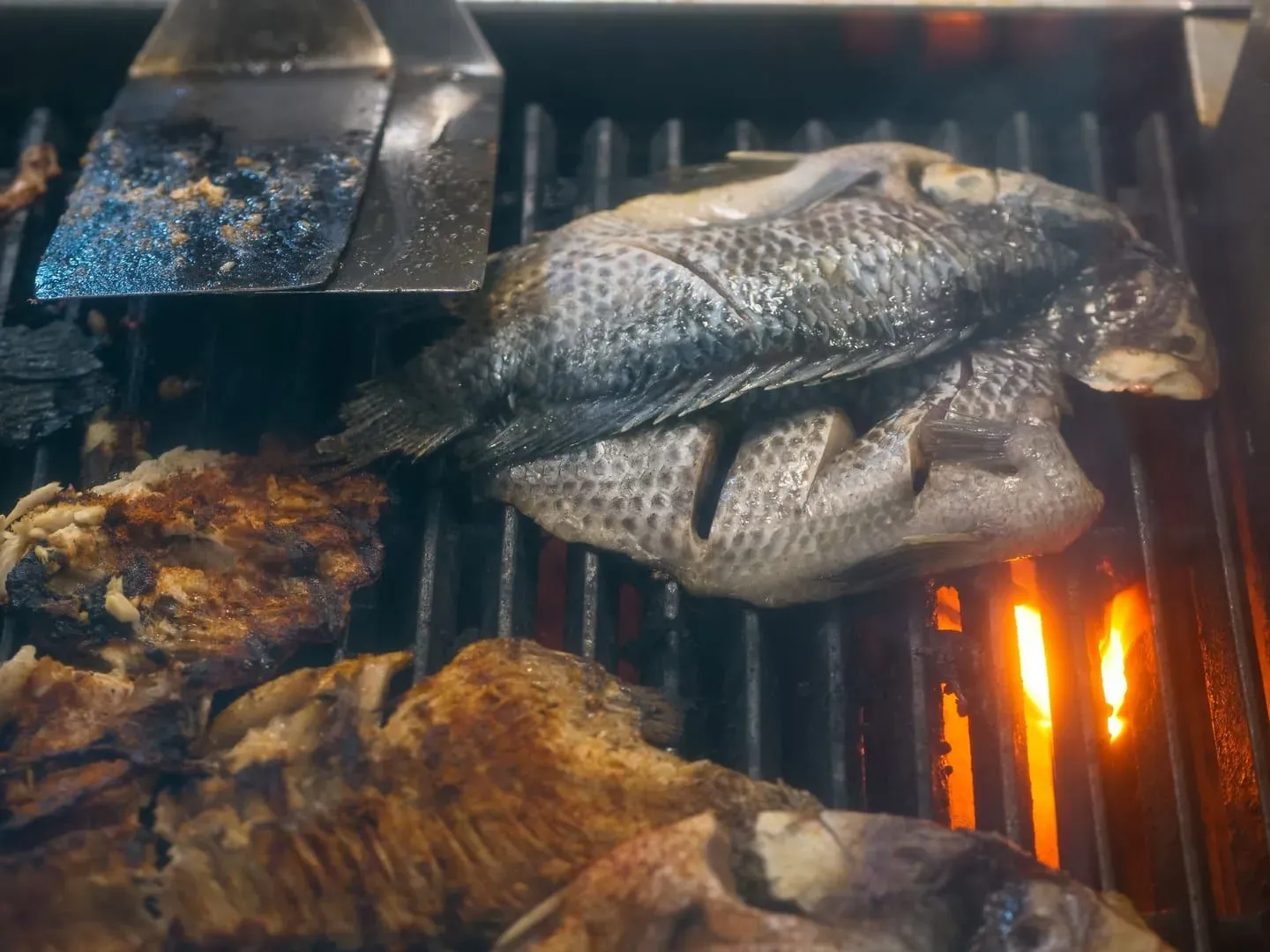 Close-up of fresh fish grilling on a charcoal grill at a Koh Samui roadside food stall