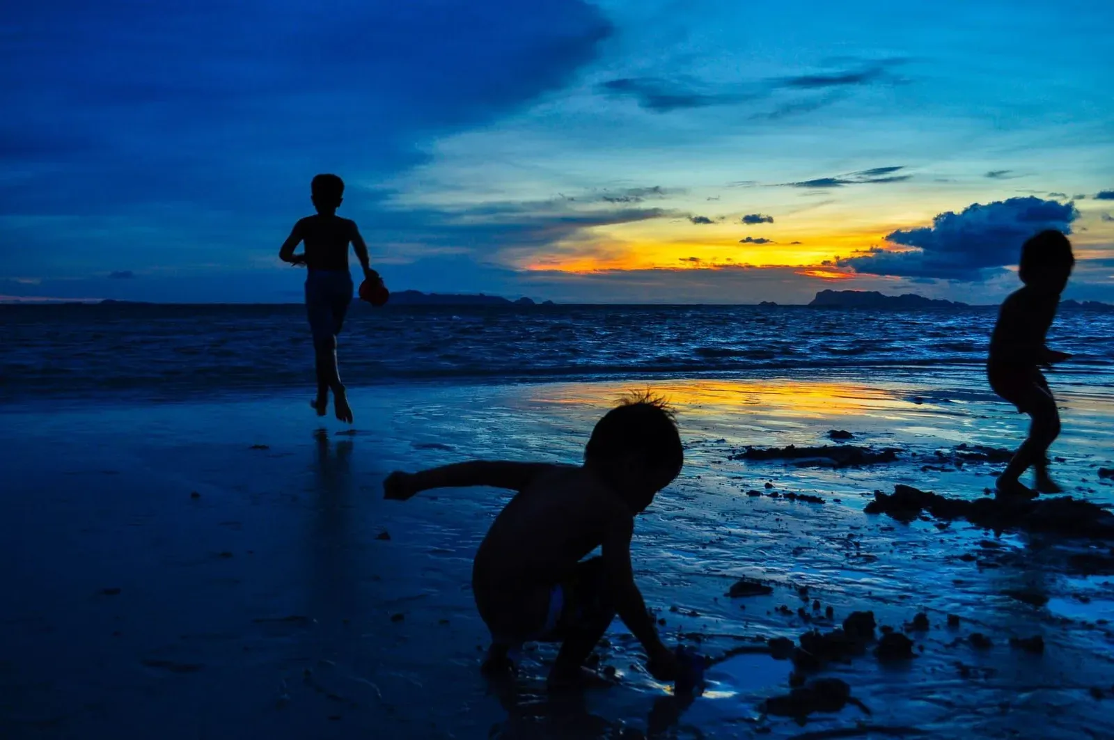 Silhouettes of children enjoying a free Koh Samui beach at sunset