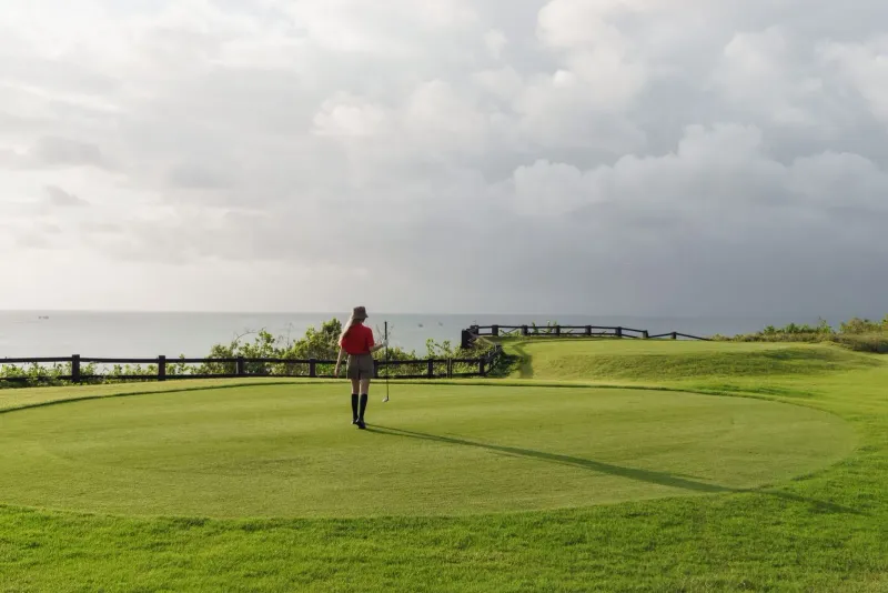Golfer on a scenic coastal golf course under a partly cloudy sky in Koh Samui