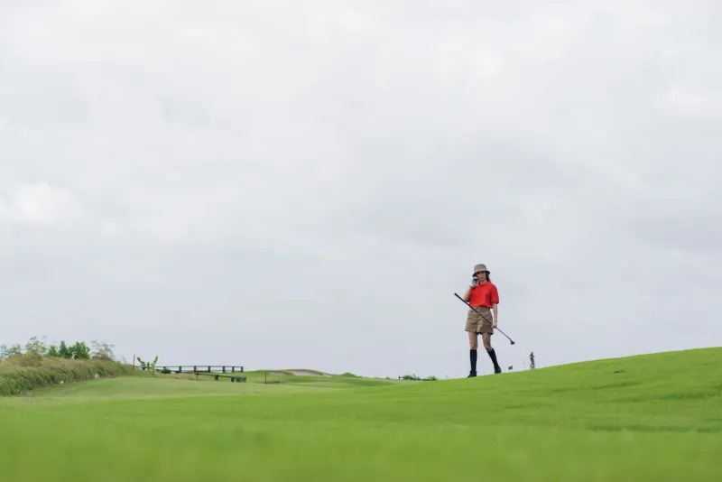 Golfer walking a tropical fairway representative of Santiburi golf course Koh Samui