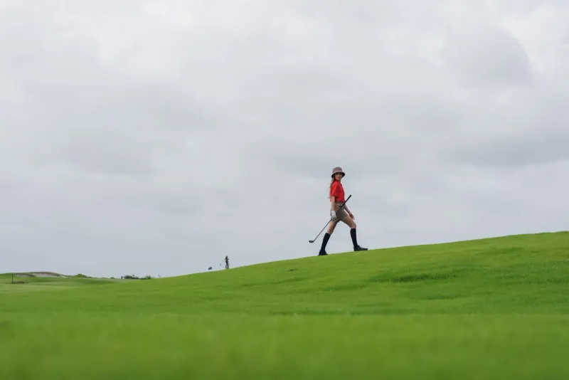 Golfer carrying a club while walking a fairway on a cloudy day on koh samui golf course