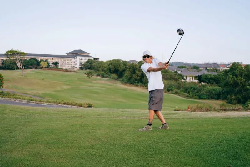 Golfer swinging a club on a lush green course, representative of golf courses koh samui