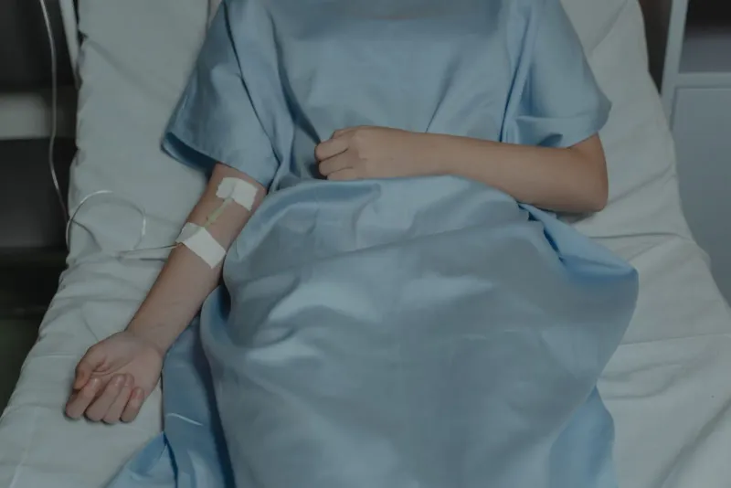Patient resting in a hospital bed with an IV drip during treatment on Koh Samui