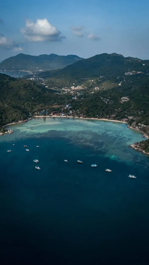 Aerial shot of a Gulf of Thailand island coastline with lush mountains near Koh Samui