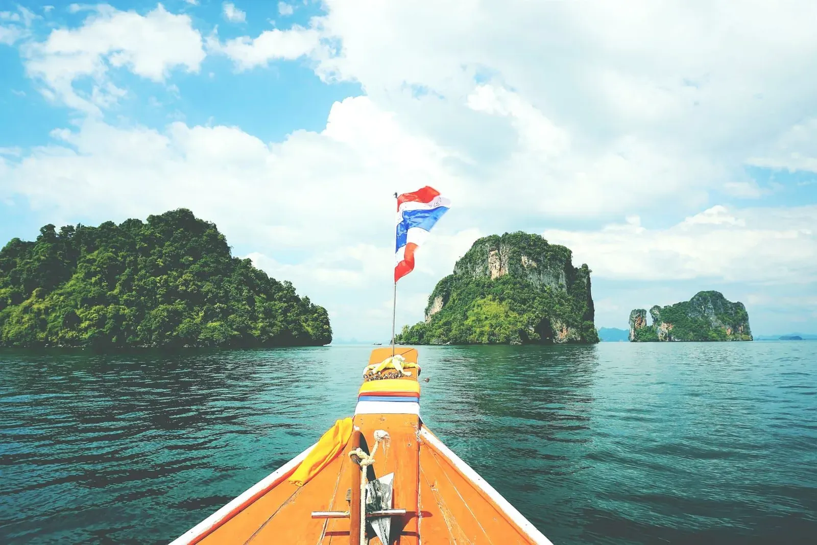Long-tail boat sailing toward lush green islands near Koh Samui on a clear day
