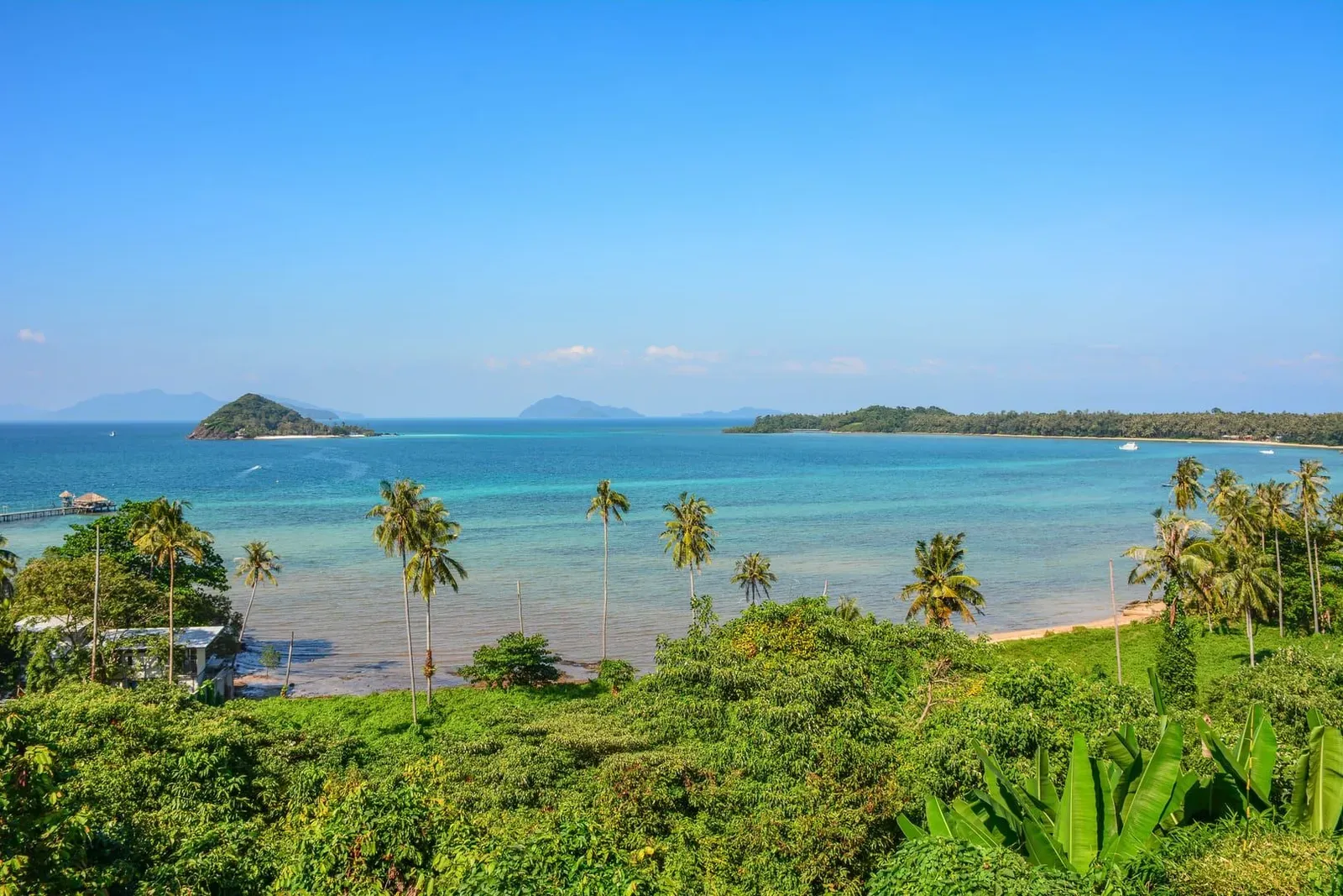 Clear blue water and green palm-lined shoreline typical of Koh Samui's lush landscape in August