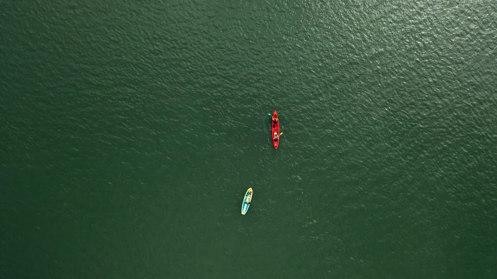 Kayaker and stand-up paddleboarder crossing calm turquoise water side by side off Koh Samui's north coast