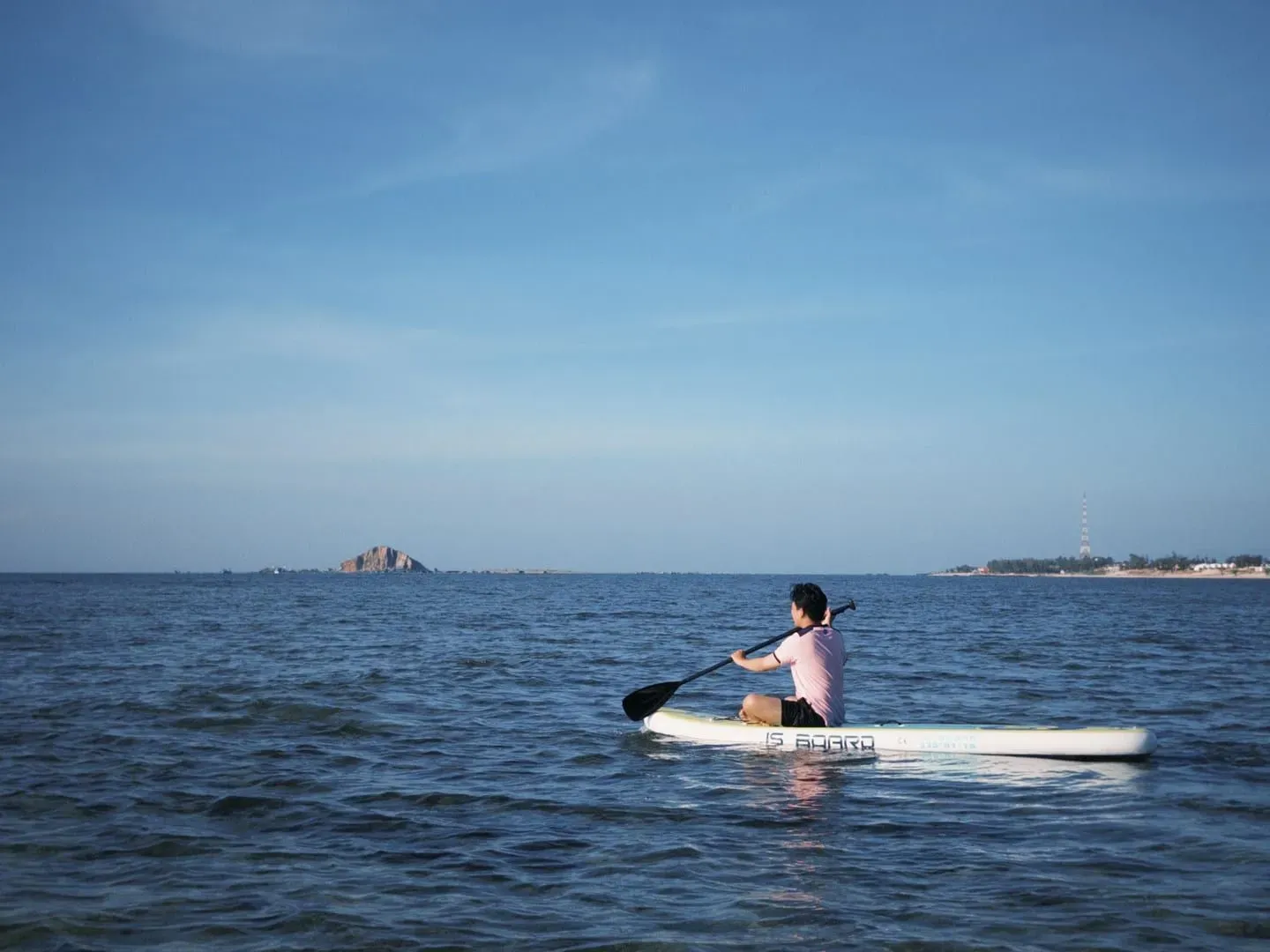 A paddler alone on flat, glassy water, the calm morning conditions that suit foiling around Koh Samui
