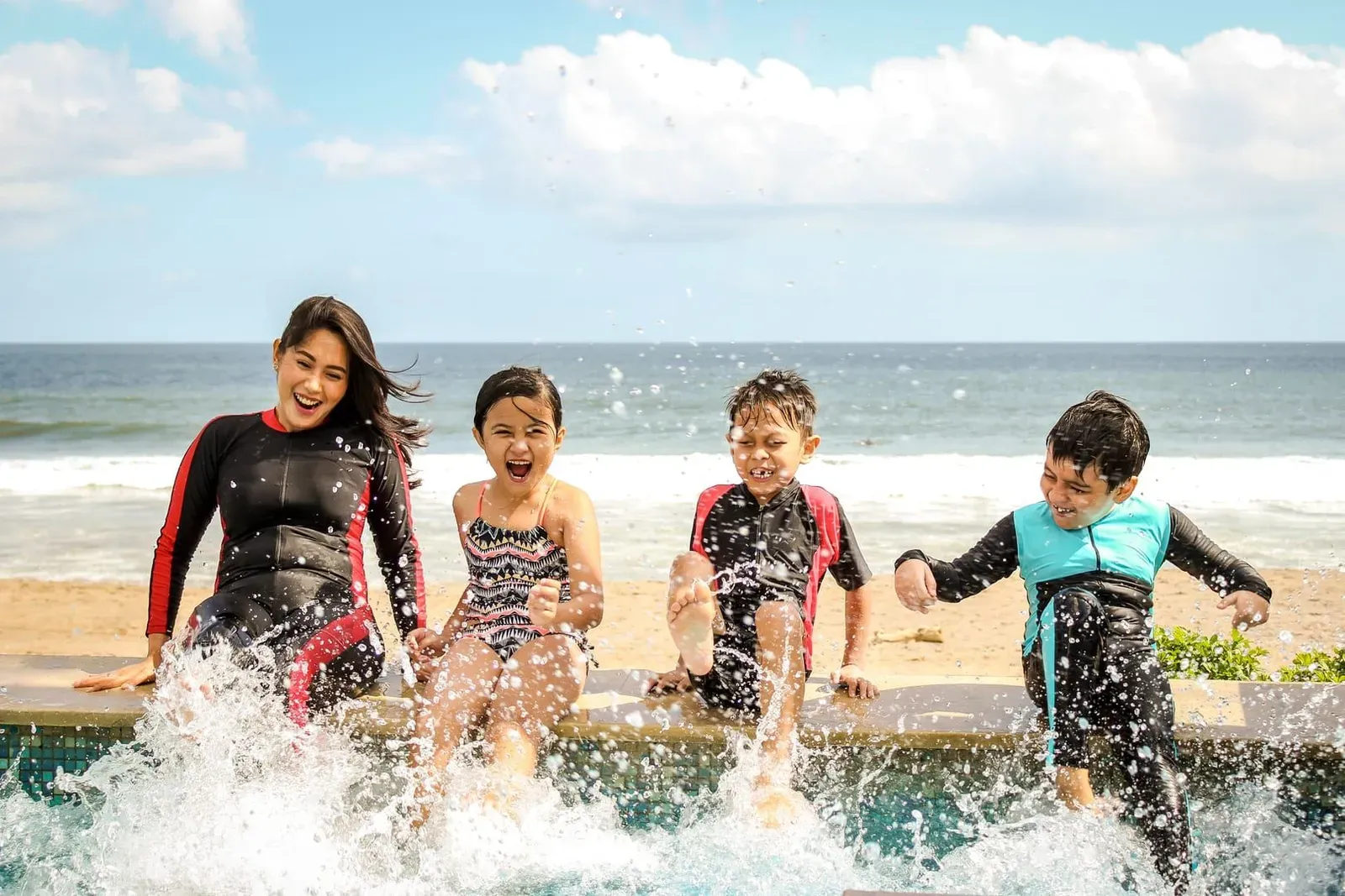 Family splashing and playing together in shallow water near the shore on a sunny day
