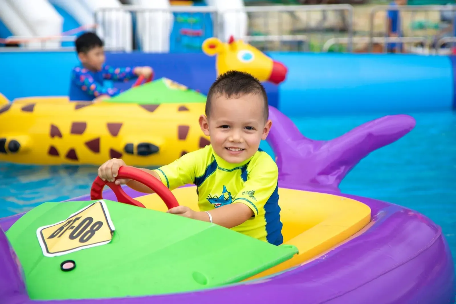 Young boy smiling while riding an inflatable float at a Koh Samui water park