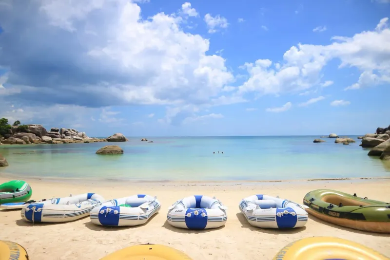 Calm beach with inflatable boats, similar to Koh Samui's family-friendly shoreline