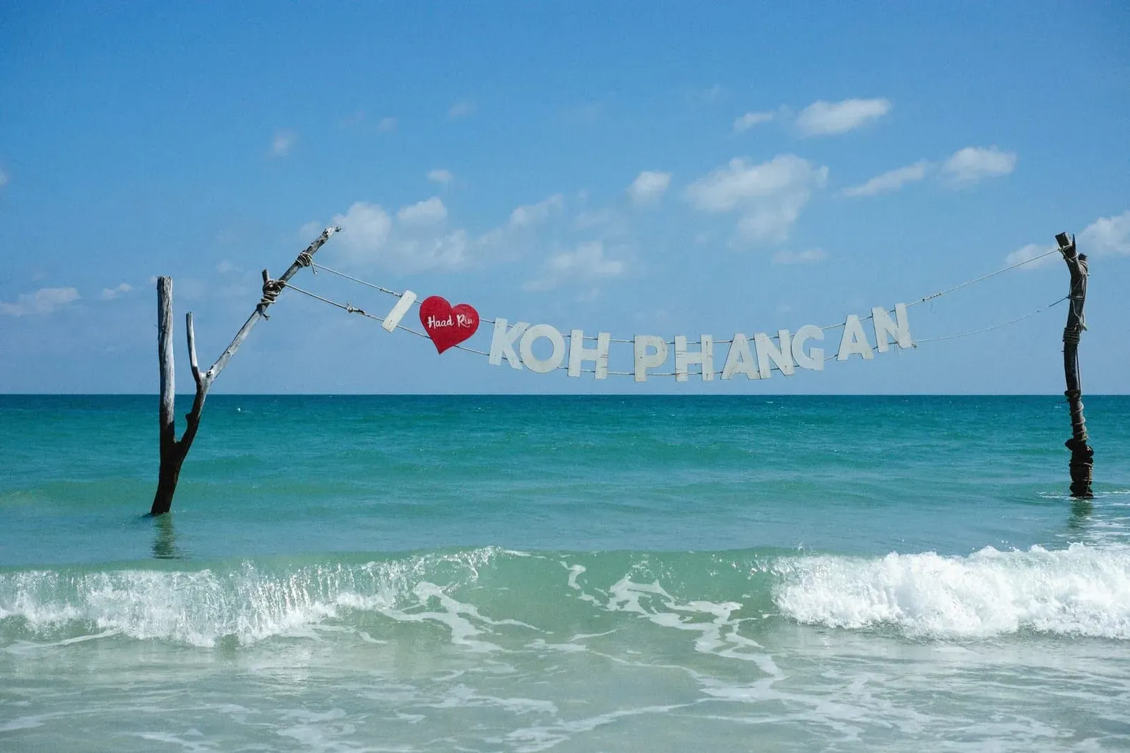 Ocean waves breaking on a Koh Phangan shoreline with a welcome sign, one of two optional island add-ons on this 10-day Koh Samui itinerary