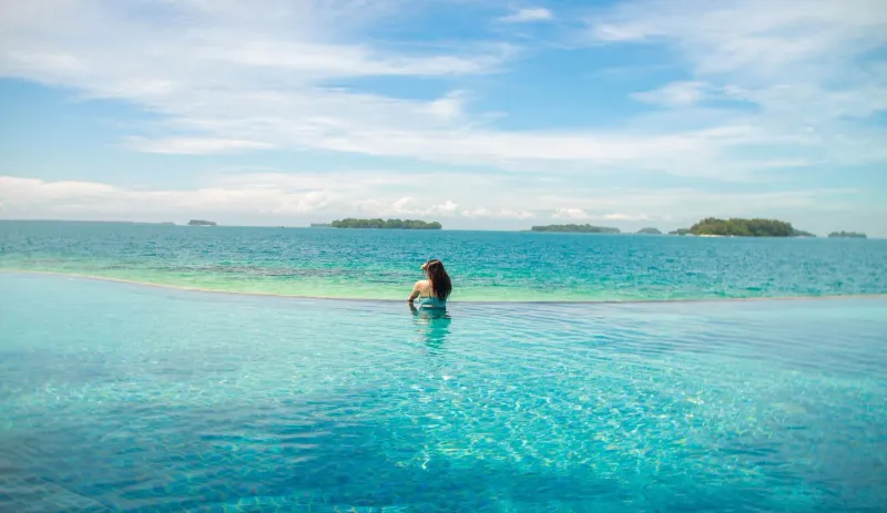 Woman relaxing in an infinity pool overlooking the sea at a Koh Samui resort