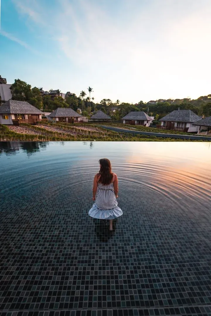 Guest standing in an infinity pool at sunset at a Koh Samui five-star resort