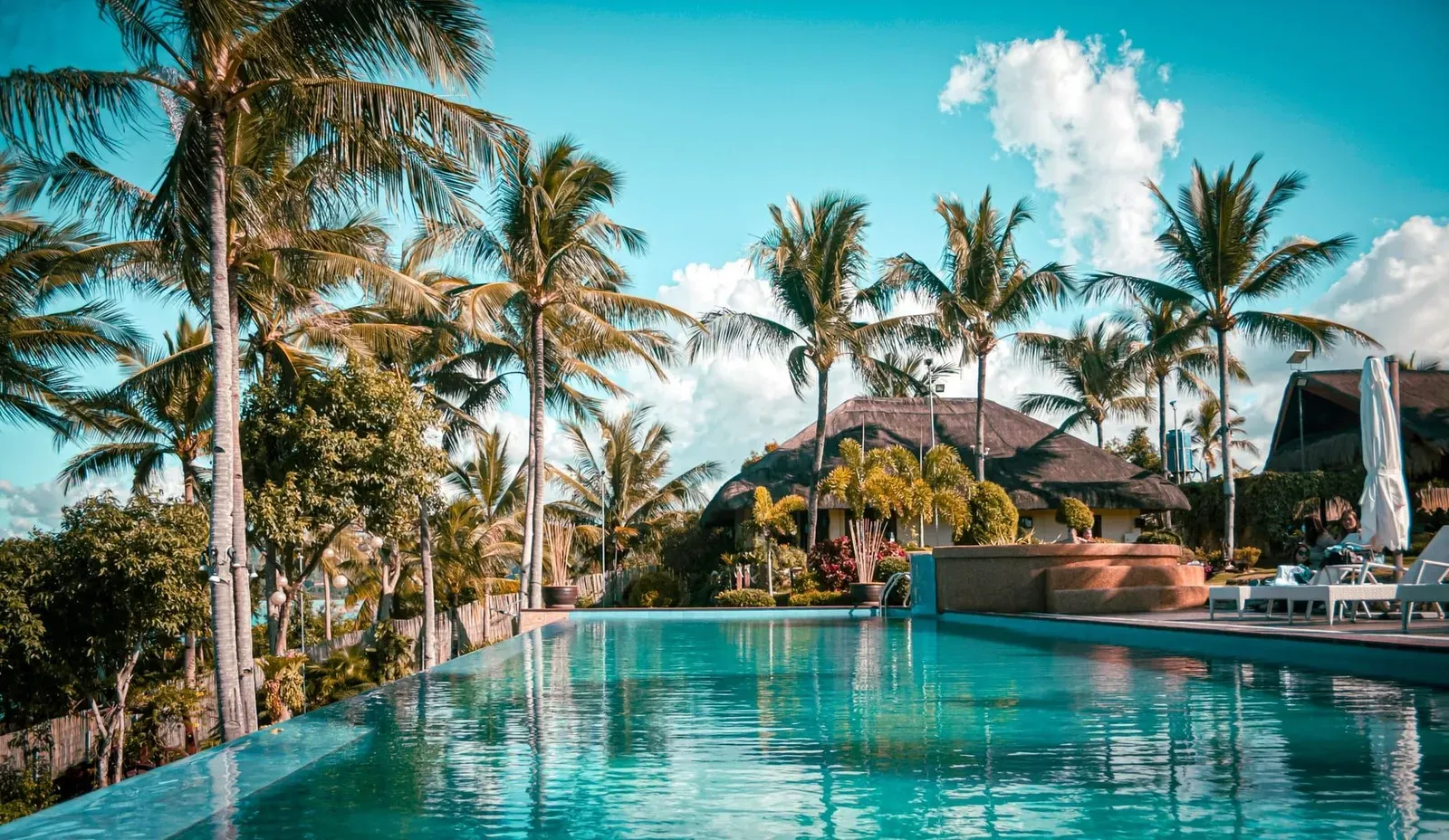 Tropical hillside resort pool with palm trees overlooking Choeng Mon Bay in Koh Samui