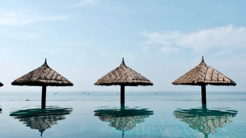 Thatched umbrellas reflecting in a tranquil infinity pool near Bophut Koh Samui