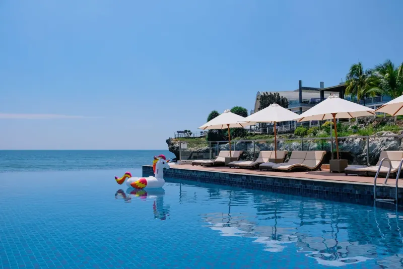 Piscina a sfioro sulla spiaggia con lettini e ombrelloni vicino a un resort tropicale a Koh Samui