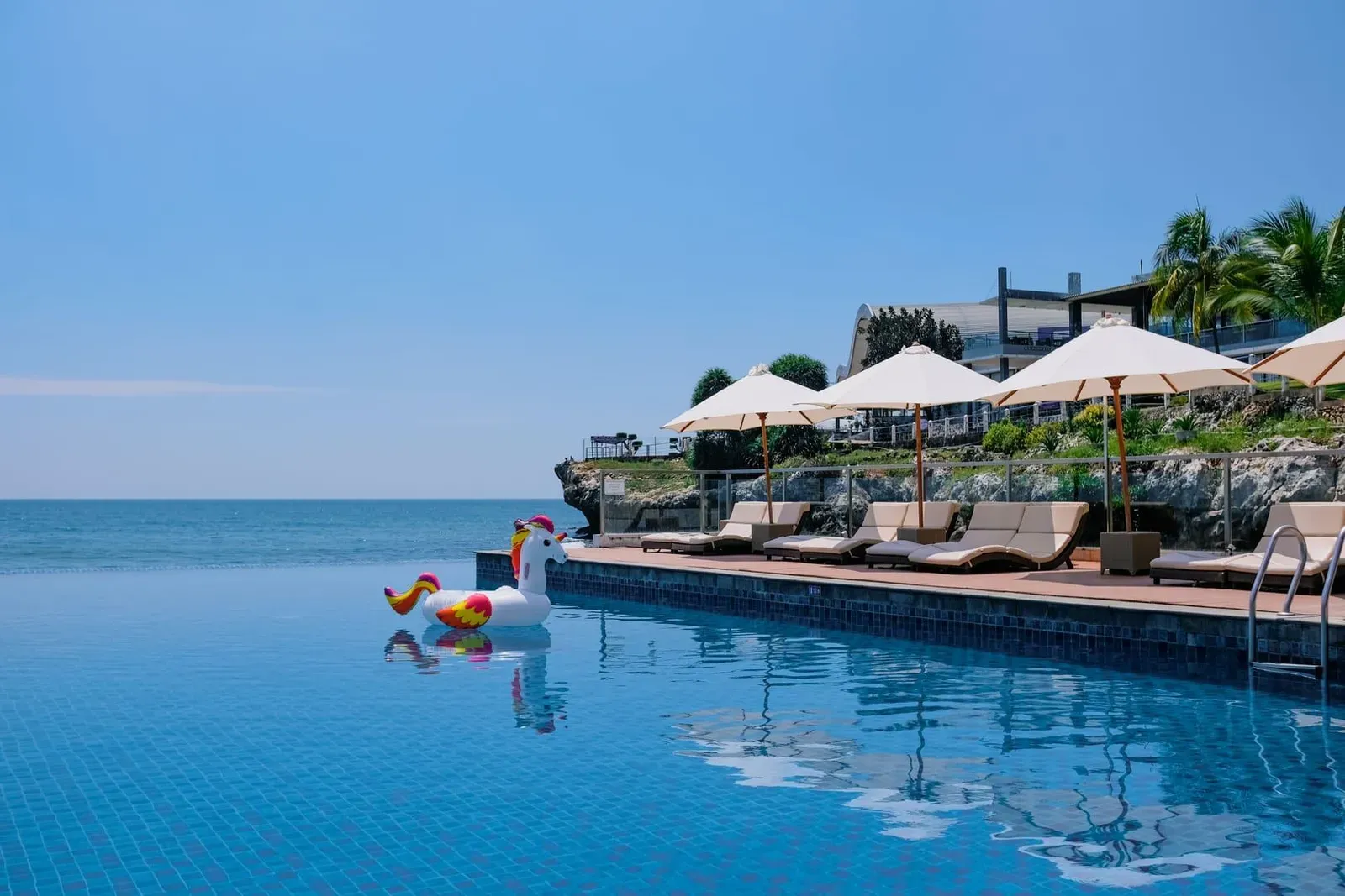 Beachside infinity pool with sunbeds and umbrellas near a tropical resort in Koh Samui