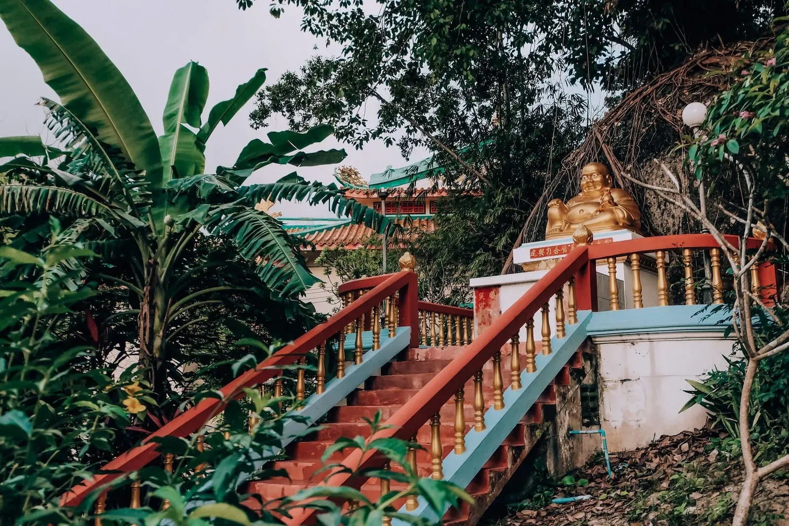 Golden Buddhist statue on temple garden steps representing mainland Thailand monastery grounds
