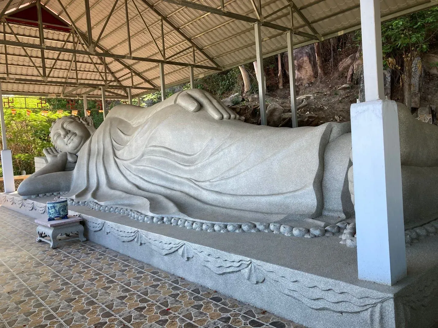 Stone reclining Buddha statue in a quiet temple courtyard near Koh Samui