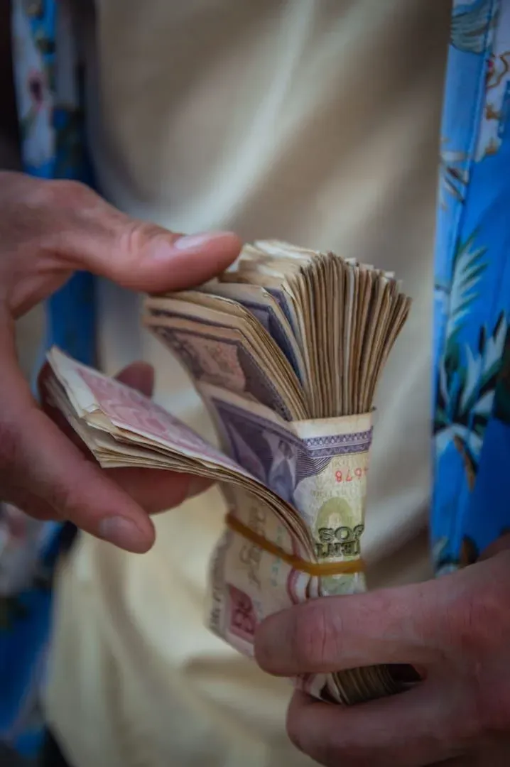 Hands counting a bundle of banknotes, illustrating daily budget planning for a Koh Samui trip
