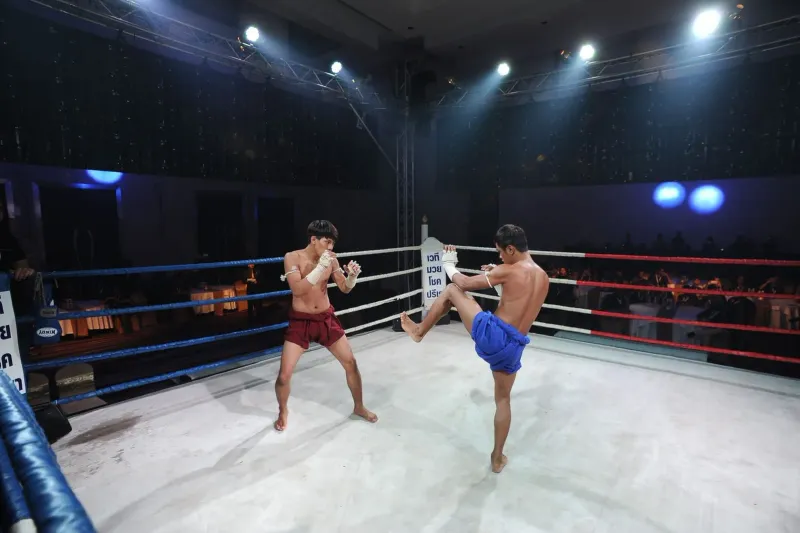 Two fighters in an intense Muay Thai match at a Thai boxing stadium