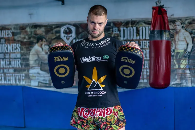 Kickboxer holding training pads showcasing muay thai gym attire