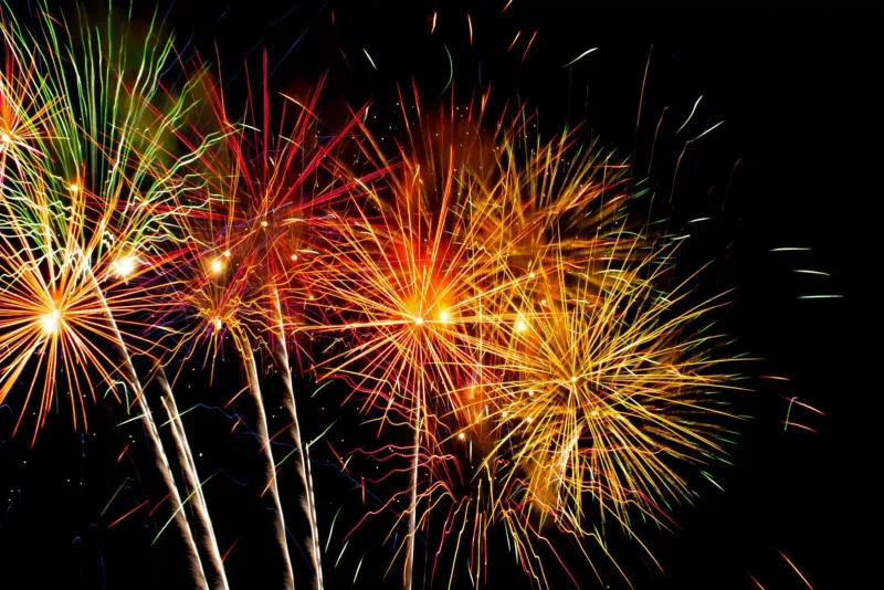 Colorful fireworks exploding over the night sky above a tropical island New Year's Eve party