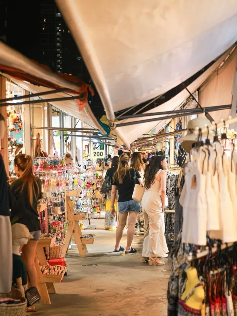 Shoppers browsing souvenir and clothing stalls at a busy Koh Samui walking street