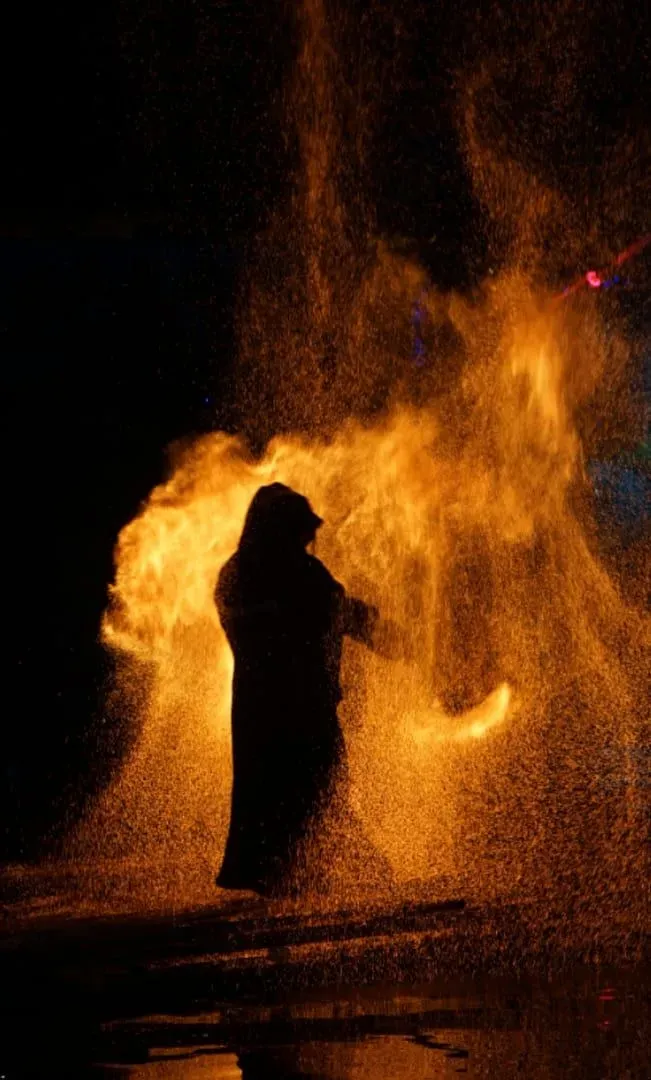 Silhouette of a fire dancer against dramatic flames at night on Koh Samui