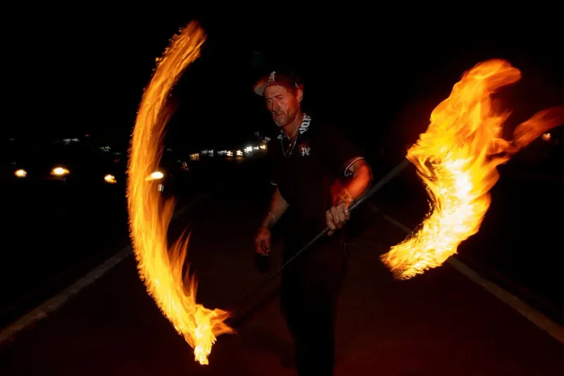 Performer twirling a flaming staff during a nighttime beach show on Koh Samui