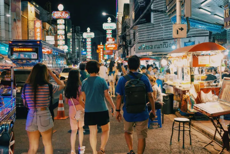 Shoppers exploring a lively night market lane on Koh Samui under string lights