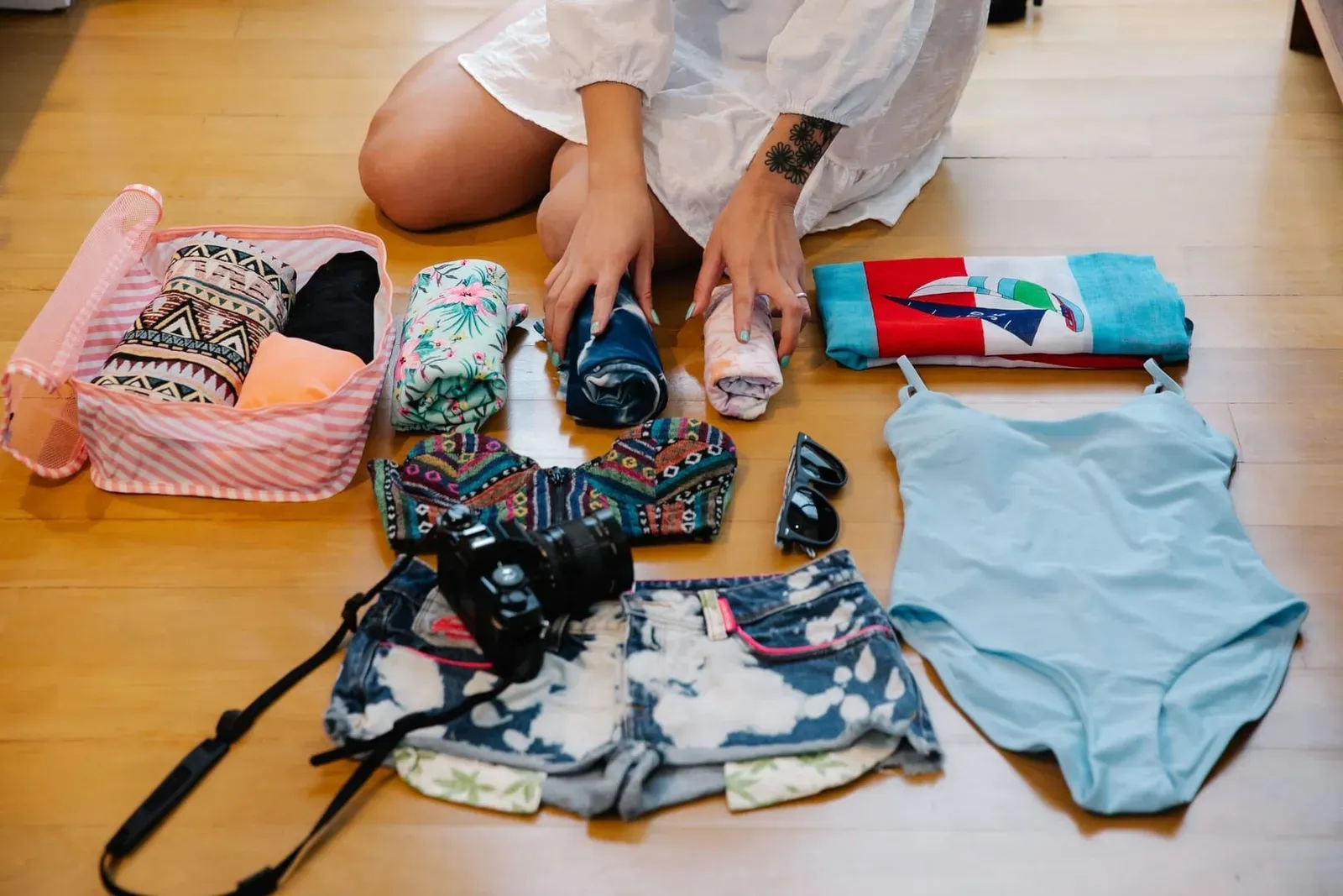 Traveler organizing clothes, camera and towel while packing for a Koh Samui trip