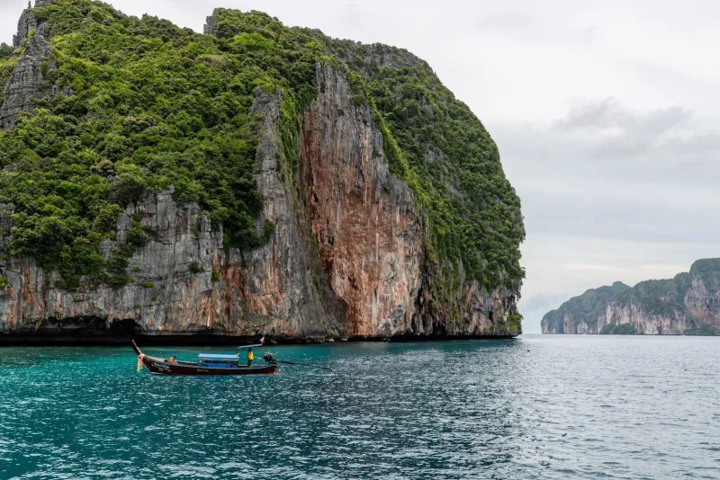 Longtail boat navigating past limestone cliffs typical of island hopping trips near Koh Samui
